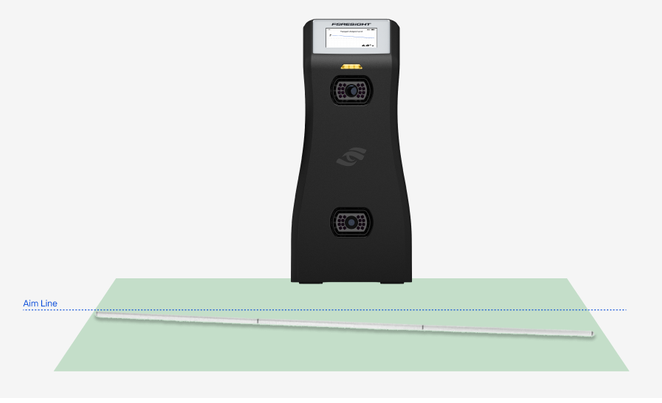 Front view showing how to set target alignment on the GC2. The 3-segment alignment stick lies flat on the ground in the hit zone in front of the GC2's cameras, running across the front of the device and pointed toward the intended target. The stick sits at a slight angle to a dotted line labeled "Aim Line," which shows the default alignment. The GC2 detects the stick, the Status Light turns yellow, and the display shows the Target Alignment screen with the adjusted angle. Remove the stick from the hit zone before hitting.